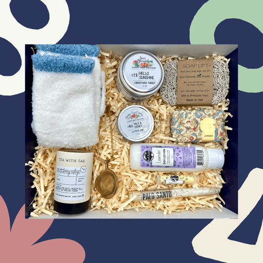 Gift box with various items including a towel, candles, and soaps on a colorful abstract background