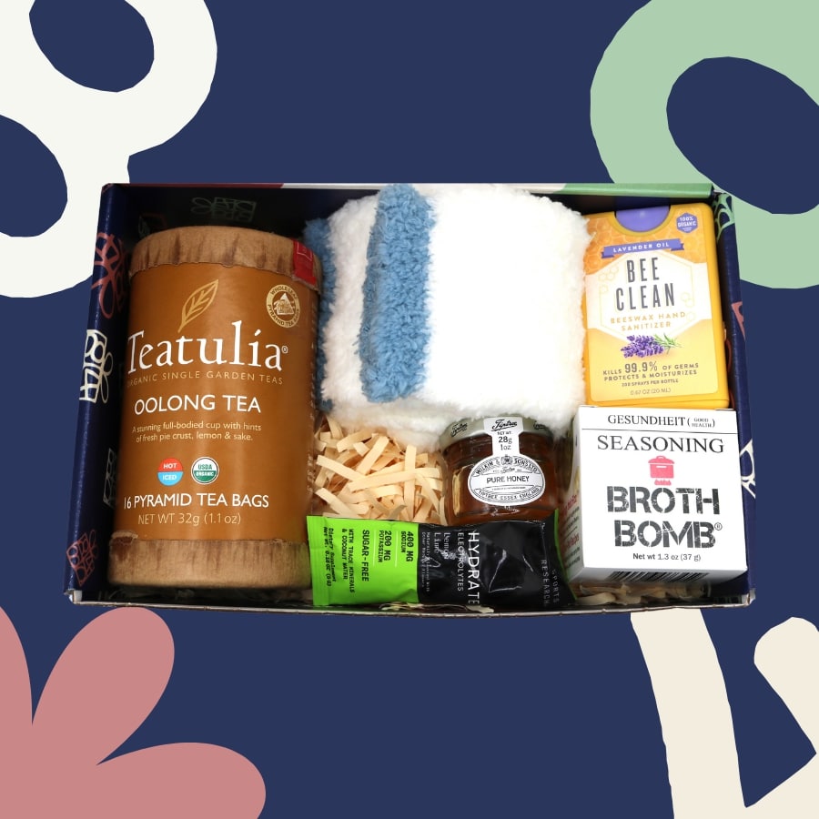 Assorted items including tea, cleaning supplies, and broth bomb in a box on a colorful background