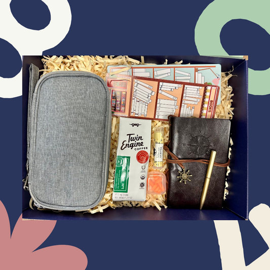 gift box with journal, traveling case, bookmarks, lip balm, earplugs, and twin engine coffee; shown in the box as if someone were opening it