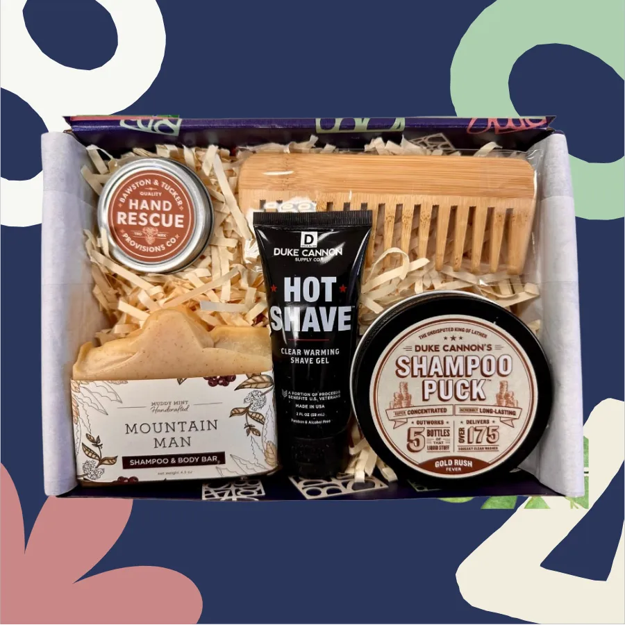 Grooming kit with Duke Cannon products including a shampoo puck, hot shave gel, and mountain man soap on a colorful background.