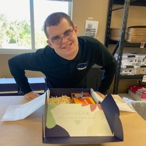 student trainee with a box of food in an indoor setting