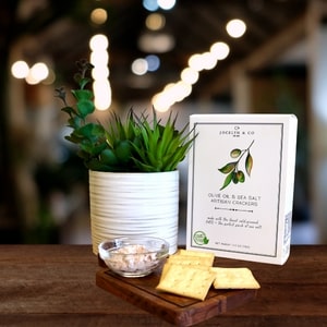 Table setting with a plant, crackers, and a box of olive oil soap.