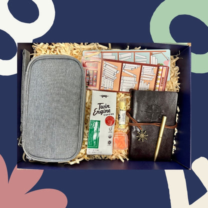 Gift box with a gray pouch, notebook, bookmarks, Twin Engine Coffee, and other items on a blue background
