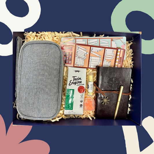 Gift box with a gray pouch, notebook, bookmarks, Twin Engine Coffee, and other items on a blue background