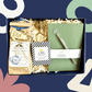 Gift set with tea package, notebook, and pen on a blue background