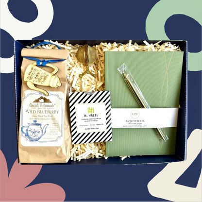 Gift box with tea package, notebook, and pen on a colorful abstract background
