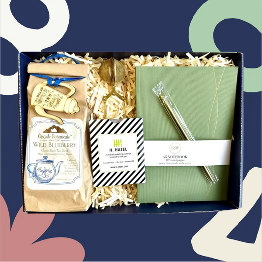 Gift box with tea package, notebook, and pen on a colorful abstract background