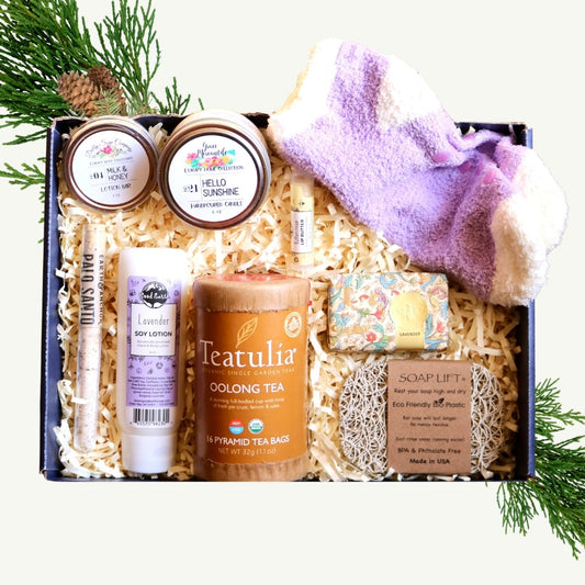 Gift basket with various items including a candle, soap, and tea on a white background