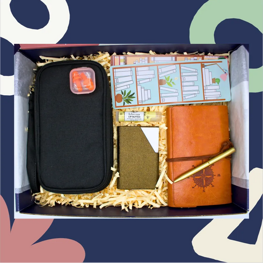 Gift set with black case, orange notebook, and other items in a box against a colorful abstract background.