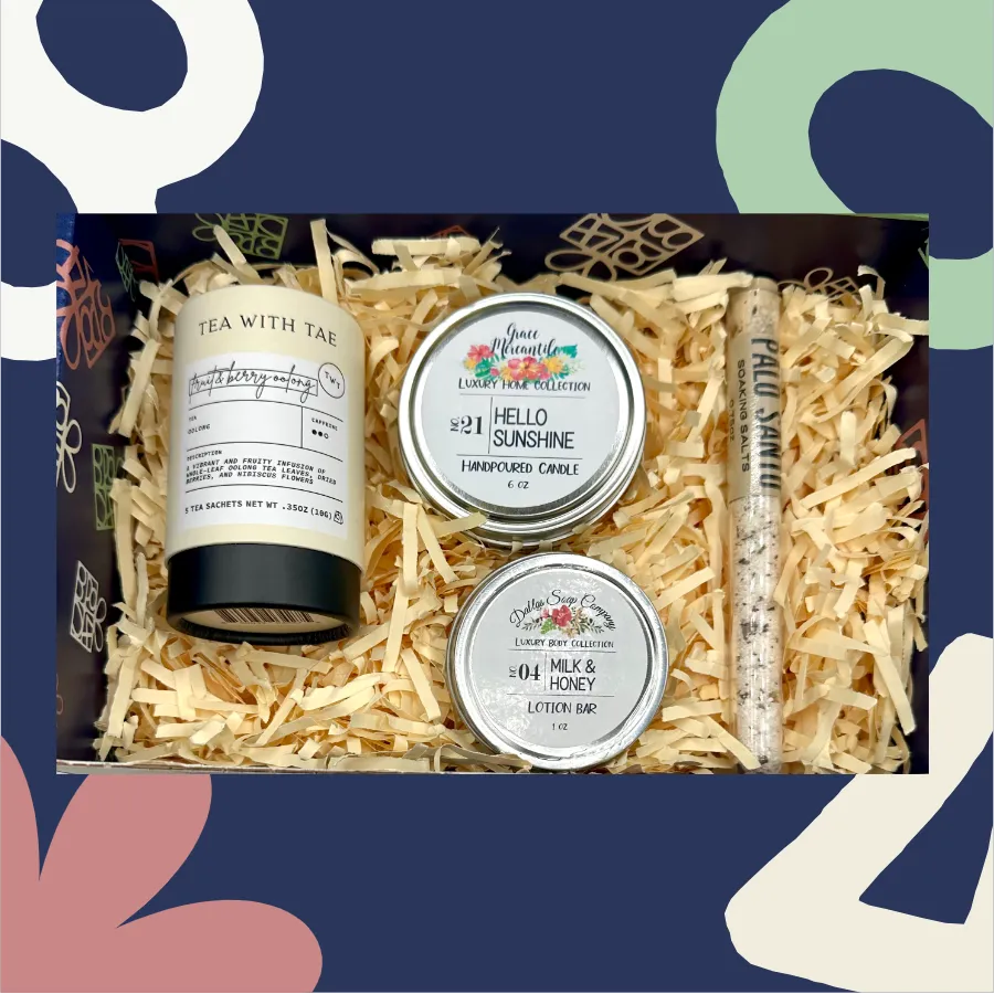 Gift set with 'Tea with Tea' product, 'Hello Sunshine' candle, 'Honey' lotion bar, and a small tube of cream on shredded paper.