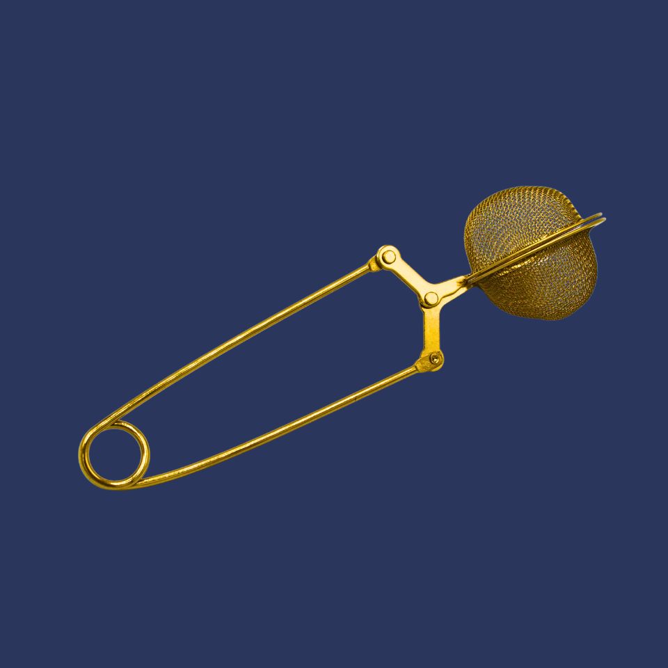 Gold-colored tea infuser on a dark blue background