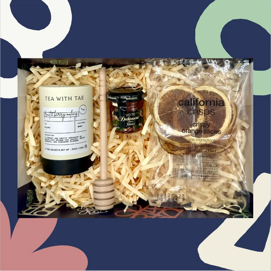 Gift set with tea, honey dipper, and orange slices on a decorative background