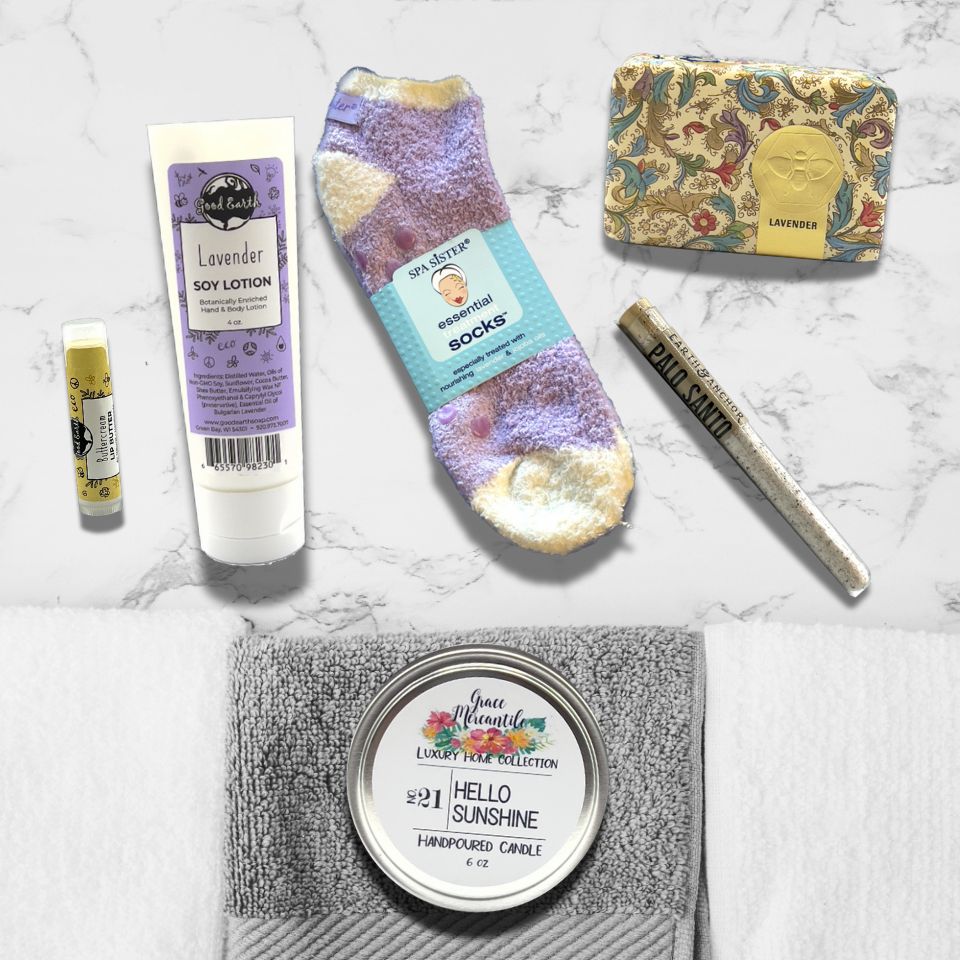 Collection of self-care products including lotion, socks, and candles on a marble surface