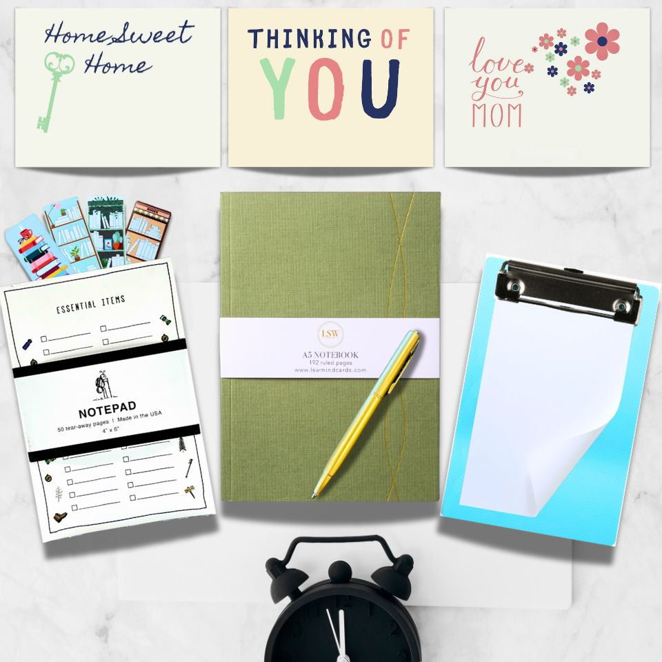 Collection of stationery items including notebooks, a pen, and a clipboard on a white surface.