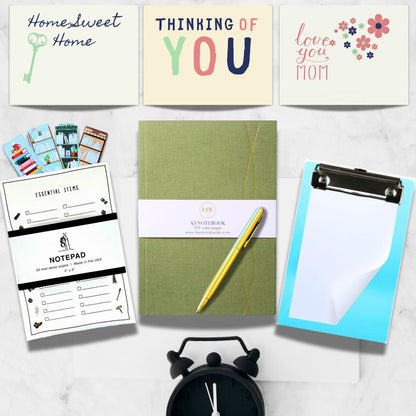 Collection of stationery items including notebooks, a pen, and a clipboard on a white surface.