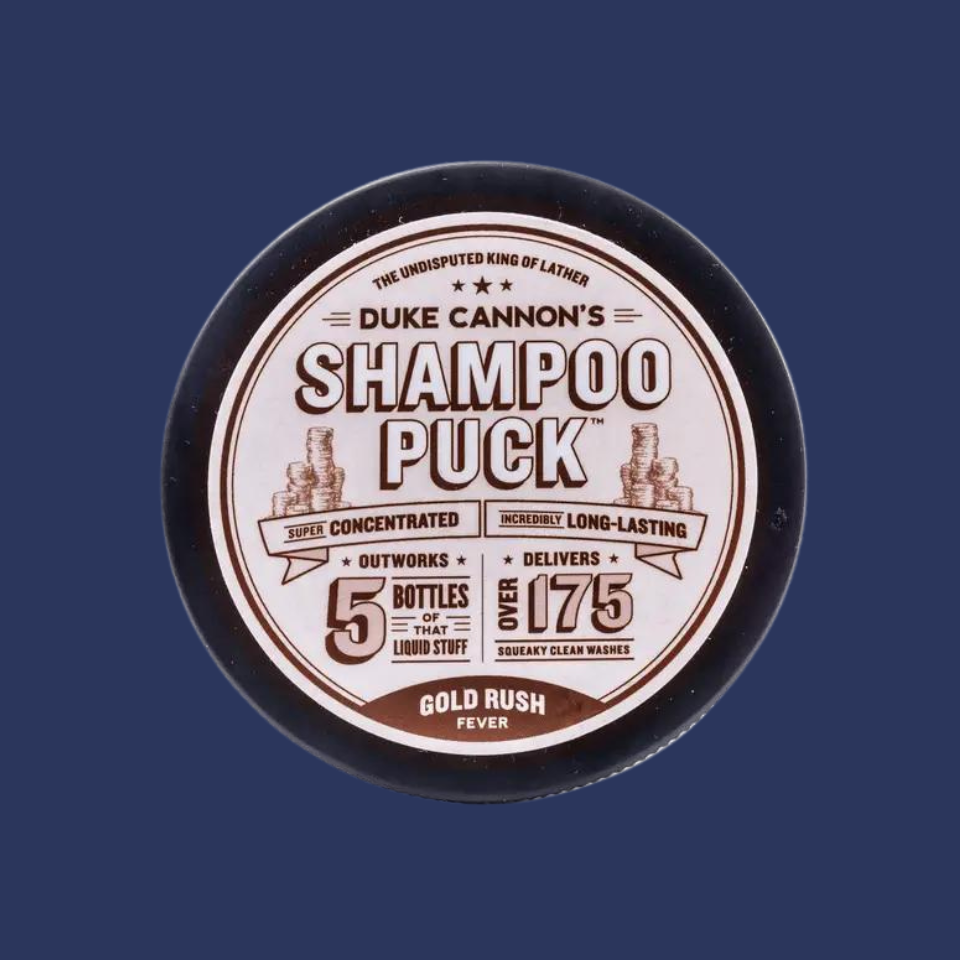 A round container of Duke Cannon's Shampoo Puck with label displaying product information and branding.
